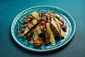 Salat mit Kalbfleisch. Kalbfleisch, Rucola, Parmesan Käse und Tomaten. Nahaufnahme, grau Hintergrund. foto