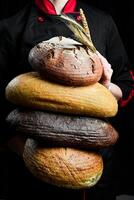 Hintergrund von Brot und Gebäck. ein Sortiment von Brot im das Hände von ein weiblich Bäcker. oben Sicht. foto