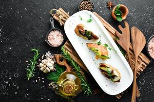 ein einstellen von Bruschetta mit Avocado, Tomaten und Fleisch. Antipasti kalt Snacks. Restaurant Speisekarte. auf ein Weiß Platte. foto