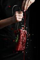 das Koch ist halten ein Stück von roh Kalbfleisch. Fleisch. auf ein schwarz Hintergrund. foto