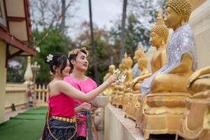 Songkran Tag, jung thailändisch Menschen tragen thailändisch Kostüme zu baden Buddha Statuen und abspielen auf Songkran Tag. foto