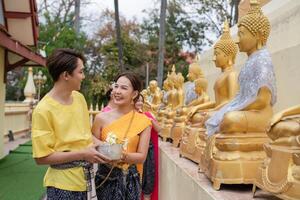 auf Songkran Tag, jung thailändisch Menschen tragen thailändisch Kostüme zu baden Buddha Statuen und abspielen auf Songkran Tag. foto