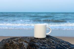 Weiß Kaffee Tasse auf das Felsen beim Meer. foto