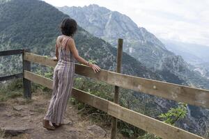 Frau Stehen auf ihr zurück gelehnt auf hölzern Geländer im schön asturisch Landschaft foto