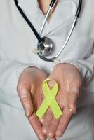 Gelb Krebs Bewusstsein Band im das Hände von ein Arzt. Welt Krebs Tag foto