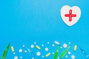 pharmazeutische Hintergrund. Pillen, Ampullen und ein hölzern Herz mit ein rot Kreuz von Tabletten auf ein Blau Hintergrund. Apotheke und Gesundheitswesen Konzept foto