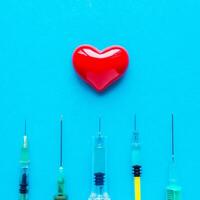 volumetrisch Herz mit Spritzen auf ein Blau Hintergrund. das Konzept von unterstützen Patienten mit Herz Krankheit foto