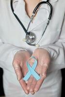 Blau Krebs Bewusstsein Band im das Hände von ein Arzt. Welt Krebs Tag foto