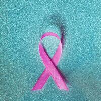 Rosa Band zum Brust Krebs Bewusstsein, symbolisch Bogen Farbe erziehen Bewusstsein auf Menschen Leben mit Damen Brust Tumor Erkrankung. Bogen isoliert mit Ausschnitt funkeln Blau Hintergrund foto