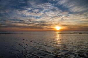 Sonnenuntergang, beleuchtet Meer. sandig Strand im das Vordergrund. Licht Wellen. baltisch Meer foto
