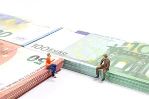 Miniatur Geschäftsmann navigiert das finanziell Landschaft, umgeben durch Euro Banknoten, foto