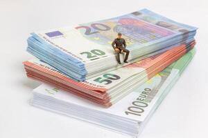 Miniatur Geschäftsmann navigiert das finanziell Landschaft, umgeben durch Euro Banknoten, foto