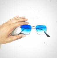 ein Hand halten ein Paar von Blau Sonnenbrille foto