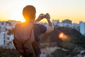 jung Mann nehmen ein Foto mit seine Kamera beim Sonnenuntergang, mit Raum zum Text