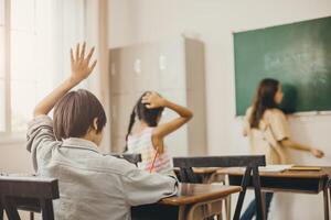 Kinder Bildung im das Schule Klasse Zimmer. Junge Hand erhebt euch zum fragen Lehrer Problem foto