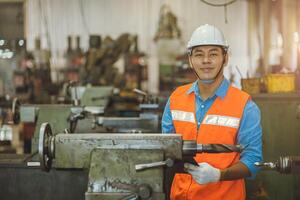 Porträt asiatisch Ingenieur Erwachsene männlich Arbeiter im Maschine Geschäft mit prüfen aufführen glücklich Lächeln im Sicherheit Helm foto