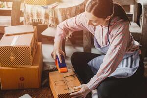 Frau Verpackung Produkte bestellen Box senden zu Kunde freiberuflich Arbeit zum besitzen Geschäft beim Zuhause Jahrgang Ton foto