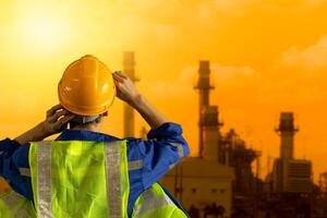petrochemisch Industrie Ingenieur suchen zurück Aussicht beim groß Petroleum Industrie Fabrik Sonnenuntergang Himmel Aussicht foto