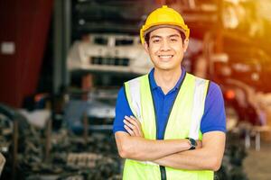 asiatisch männlich Ingenieur Arbeiter Stehen Arm gekreuzt zuversichtlich glücklich Lächeln zum genießen Arbeiten im Fabrik suchen Kamera foto