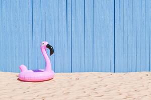 aufblasbar Rosa Flamingo auf sandig Strand mit Blau hölzern Hintergrund foto