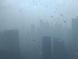 verschwommen Aussicht mit Wasser Tropfen auf das Fenster von das Wolkenkratzer Gebäude foto