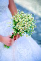 Frau im Hochzeit Kleid halten Gänseblümchen Strauß foto
