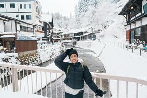 Frau Tourist Besuch Ginzan Onsen im Yamagata, glücklich Reisender Besichtigung japanisch Onsen Dorf mit Schnee im Winter Jahreszeit. Wahrzeichen und Beliebt zum Attraktion im Japan. Reise und Ferien Konzept foto