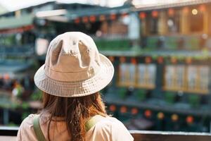 Frau Reisender Besuch im Taiwan, Tourist mit Hut und Rucksack Besichtigung im jiufen alt Straße Dorf mit Tee Haus Hintergrund. Wahrzeichen und Beliebt Sehenswürdigkeiten in der Nähe von Taipeh Stadt. Reise Konzept foto