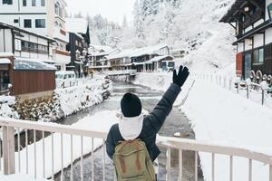 Frau Tourist Besuch Ginzan Onsen im Yamagata, glücklich Reisender Besichtigung japanisch Onsen Dorf mit Schnee im Winter Jahreszeit. Wahrzeichen und Beliebt zum Attraktion im Japan. Reise und Ferien Konzept foto