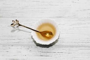 Flüssigkeit organisch Honig im ein Weiß Teller mit ein golden Dessert Löffel foto
