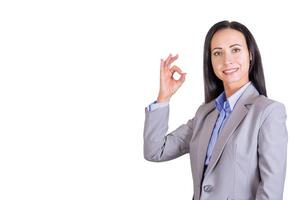 Porträt von ein lächelnd, jung attraktiv Geschäft Frau im ein Geschäft Anzug, mit ein Hand Geste OK. Geschäft Dame foto