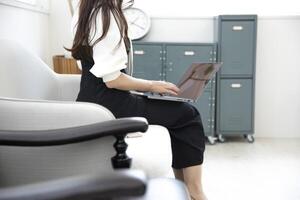 ein japanisch Frau Tippen Laptop durch Fernbedienung Arbeit im das Büro gesichtslos Komposition foto