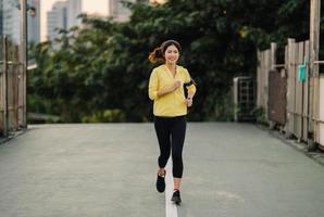 schöne junge asiatische athletin dame läuft in städtischer umgebung foto