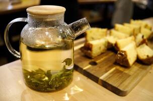 Grün Tee gebraut im ein Glas Karaffe und Nächster zu geschnitten Stücke von Cupcake. selektiv Fokus.hoch Qualität Foto