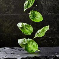 fliegend frisch natürlich Basilikum Blätter auf schwarz Stein Hintergrund foto