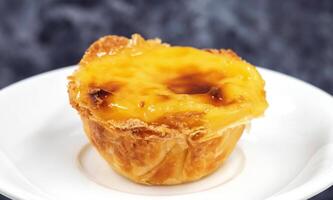 einer Pastell- de nata oder Portugiesisch Ei Torte auf ein Weiß Platte. Pastell- de Belm ist ein klein Kuchen mit ein knusprig Puff Gebäck Kruste und ein Pudding Sahne Füllung. foto