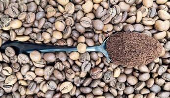 gegen das Hintergrund von geröstet aromatisch Kaffee Bohnen Lügen ein Metall Löffel gefüllt mit Boden Kaffee. ein trinken gemacht von geröstet und Boden Bohnen von das Kaffee Baum oder Kaffee Busch. foto