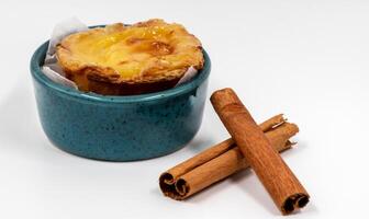 Pastell- de nata Gebäck oder Portugiesisch Ei Torte und Zimt Stöcke isoliert auf Weiß Hintergrund. Pastell- de belem ist ein klein Kuchen mit ein knusprig Puff Gebäck Kruste und ein Pudding Sahne Füllung. foto