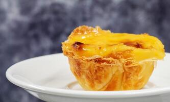 Teller mit einer Portugiesisch Pastell- de nata Quiche. Pastell- de belem ist ein klösterlich und Kult Gebäck im das bilden von Tassen mit ein verbrannt oben und ein knusprig Puff Gebäck Kruste. Süss Dessert mit Ei Creme. foto