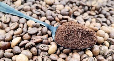 Boden Kaffee Pulver im ein Metall Löffel im das Vordergrund, gegen das Hintergrund von geröstet aromatisch Kaffee Bohnen. Kaffee Konzept. foto