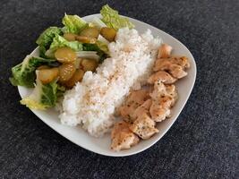 hausgemacht gegrillt Hähnchen mit Grün Salat, Reis Pilaw und Gurke Gurken serviert auf ein Weiß Teller foto