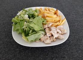 hausgemacht gegrillt Hähnchen mit Französisch Fritten und Grün Salat, serviert auf ein Weiß Teller foto