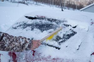 Hand Treiber mit Bürste fegen Schnee auf Windschutzscheibe Auto foto