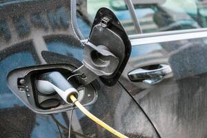 elektrisch modern Auto Laden mit Kabel Leistung liefern eingesteckt auf Bahnhof foto