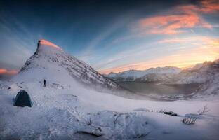 Panorama von Sonnenaufgang Über schneebedeckt Berg Angebot mit Bergsteiger Zelt Camping im Winter auf segla montieren beim Senja Insel foto