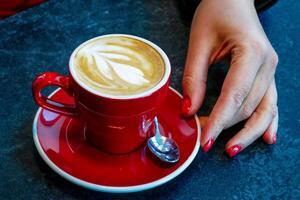 Frau Hand Nächster zu ein Tasse von Kaffee foto