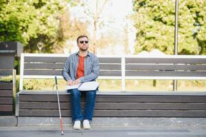 blind Mann lesen Buch auf Bank im Park foto