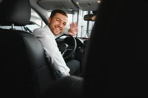 Taxi Treiber lächelnd während drehen Über zu das Rücksitz suchen reden mit Kunden. erfolgreich Geschäftsmann Mann suchen beim das Rücksitz beim Händler Geschäft Vor Kauf ein Auto foto