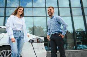 Paar auf das Laden Bahnhof zum elektrisch Fahrzeuge foto