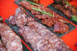 einstellen von anders Typen von Würste, Salami und geräuchert Fleisch mit Basilikum und Gewürze. oben Aussicht foto